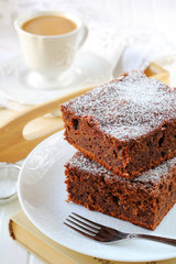 two pieces of plum cake with chocolate and almonds on a white pl