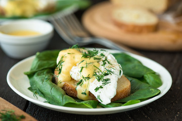 Poached egg on a piece of bread with spinach on the wooden table