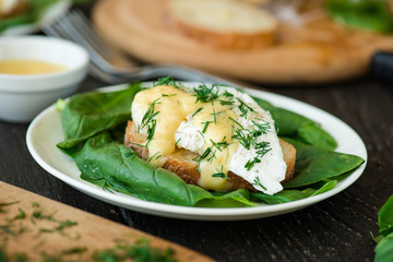 Poached egg on a piece of bread with spinach on the wooden table