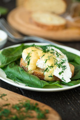 Poached egg on a piece of bread with spinach on the wooden table