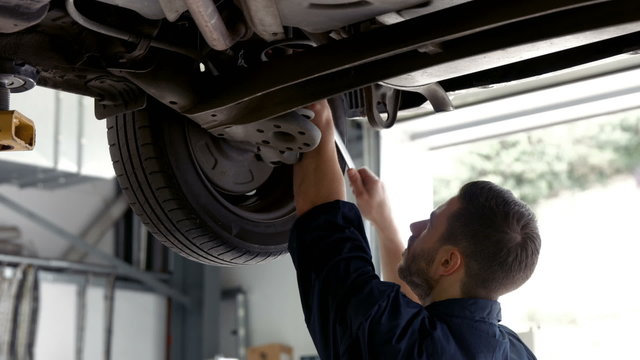 Handsome mechanic reparing a car