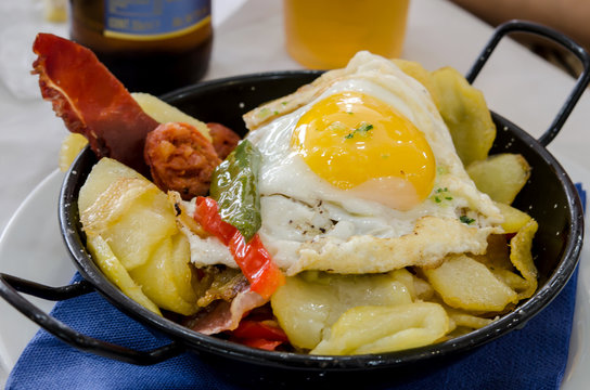 Pan with fried potatoes, fried egg, roasted peppers and sausage