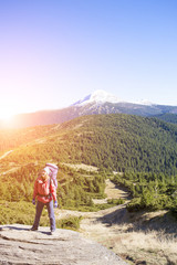 Girl with a backpack standing on a rock.