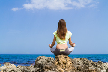 Fototapeta na wymiar Athletic teenage brunette performs yoga workout by the ocean