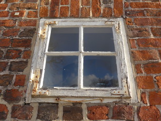  A weathered, closed wooden window in an old brick building,  Bild