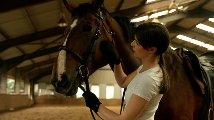 Smiling brunette stroking her horse 