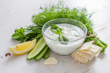 Tzatziki sauce ingredients, white wood background