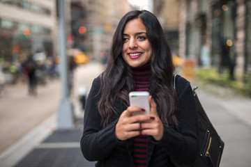 Indian woman in city texting cell phone