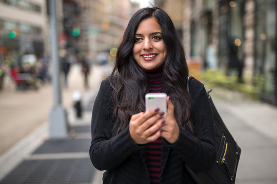 Indian woman in city texting cell phone