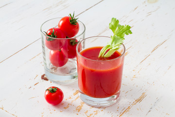 Tomato juice in glass, white wood background