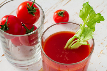 Tomato juice in glass, white wood background