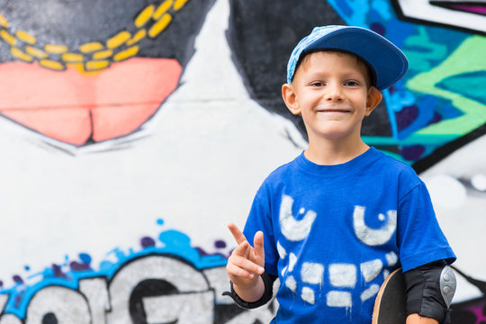 Funny kid pointing up in front of a graffiti wall