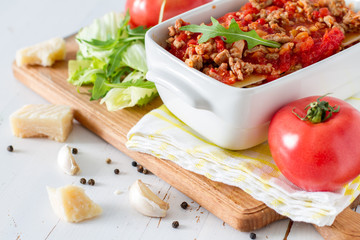 Raw lasagna and ingredients, white wood background