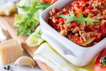 Raw lasagna and ingredients, white wood background