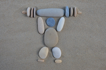 The Weightlifter, stones composition on the sand