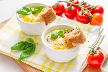 Egg cocotte  in white ramekin with tomato and basil