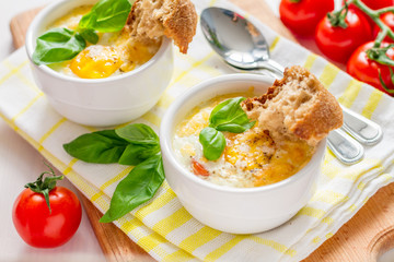 Egg cocotte  in white ramekin with tomato and basil