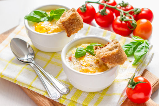 Egg cocotte  in white ramekin with tomato and basil