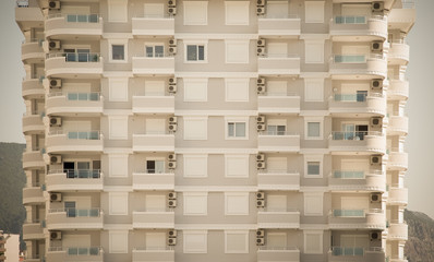 Facade of a block of flats. Sky and mountains behind. Toned