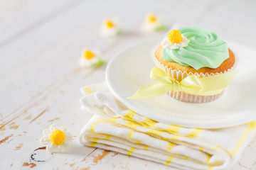 Cupcake with yellow ribbon, white wood background