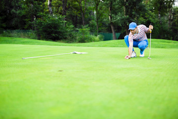 Obraz premium Golf player marking ball on the putting green