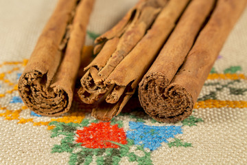 Several cinnamon sticks over a embroidered cloth