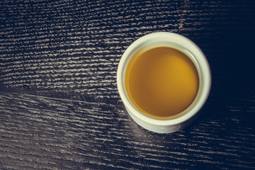 Cap of fresh olive oil on a black wooden table or board. Toned