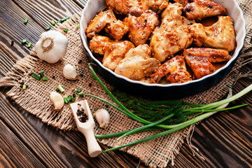 
baked chicken wings and garlic marinade with herbs on a wooden background