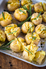 Rosemary baked potatoes with garlic and sea salt on baking tray, close up. Cooked side dish for Thanksgiving table