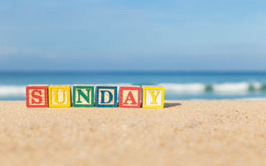 word SUNDAY in colorful alphabet blocks on tropical beach