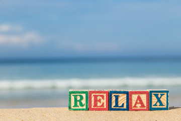 word RELAX in colorful alphabet blocks on tropical beach