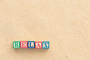 word RELAX in colorful alphabet blocks on tropical beach