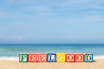 word FEELGOOD in colorful alphabet blocks on tropical beach