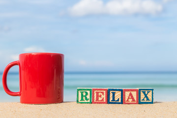 word RELAX in colorful alphabet blocks and coffee cup on tropica