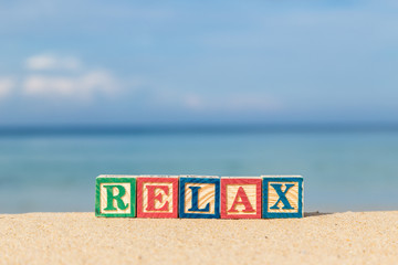 Naklejka premium word RELAX in colorful alphabet blocks on tropical beach