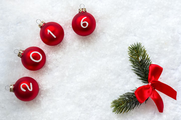 Christmas balls 2016 and fir branch on snow backgroundwith space for your text.