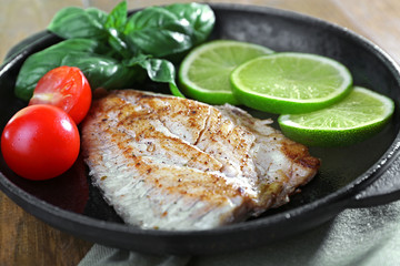 Dish of fish fillet with salad and lime on table close up