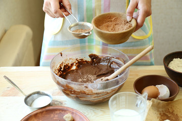 Woman preparing dough for chocolate pie on table close up