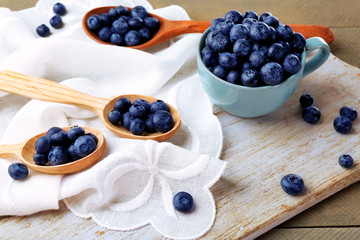 Fresh blueberries in cup and spoons on table close up