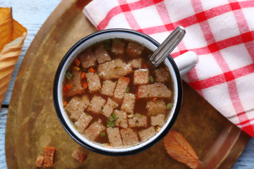 Mug of soup on metal tray on a table