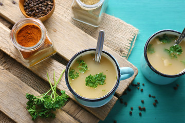 Mugs of soup on wooden mat