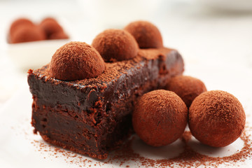 Slice of chocolate cake with a truffle on plate closeup