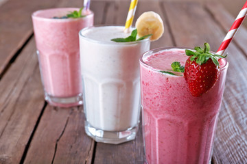 Glasses of fresh cold smoothie with fruit and berries, on wooden background