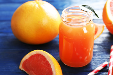 Grapefruit juice in bottles and fresh fruits on dark blue wooden background