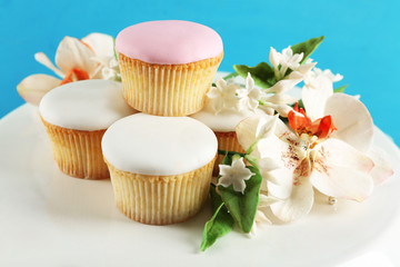 Tasty cupcakes on stand, on color wooden background