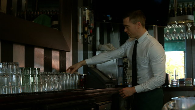Bartender using cash register and tidying up the counter
