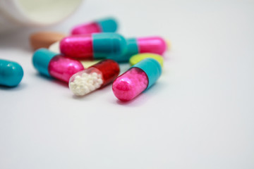 Colored pills, tablets and capsules on white background