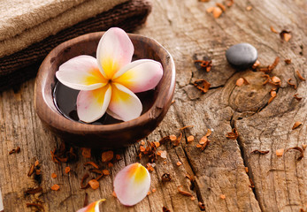Fototapeta na wymiar frangipani in bowl and stones ,dry flower petals ,towel on old wood