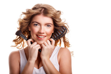 Girl with curly hair holding makeup brush and comb.