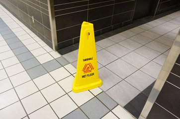 Yellow caution slippery wet floor sign labeled in English and Fr